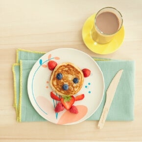 Pancakes decorated with berries and served with a glass of Nesquik